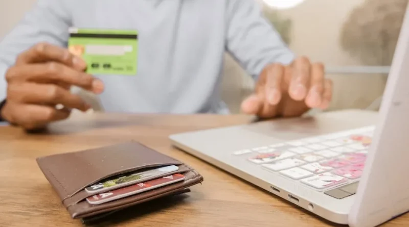 Seseorang melihat dompet kosong dengan ekspresi khawatir di meja yang penuh tagihan dan laptop, menggambarkan stres finansial.